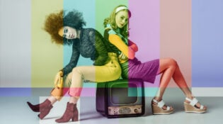 two young women sitting on a television with NTSC color bars overlay on the entire image