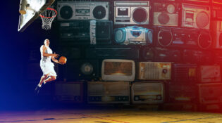 A basketball player leaps toward the hoop on an indoor court, surrounded by a dramatic collage of vintage radios and boomboxes lit in deep blue and red tones.